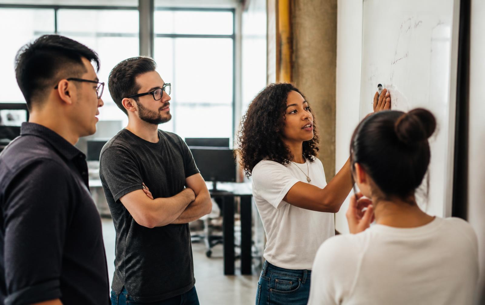 Equipe de startup discutindo um projeto em um quadro branco